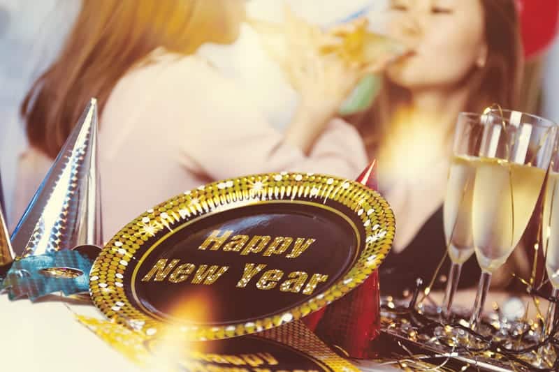 women in background drinking champagne with new year decorations and champagne on table